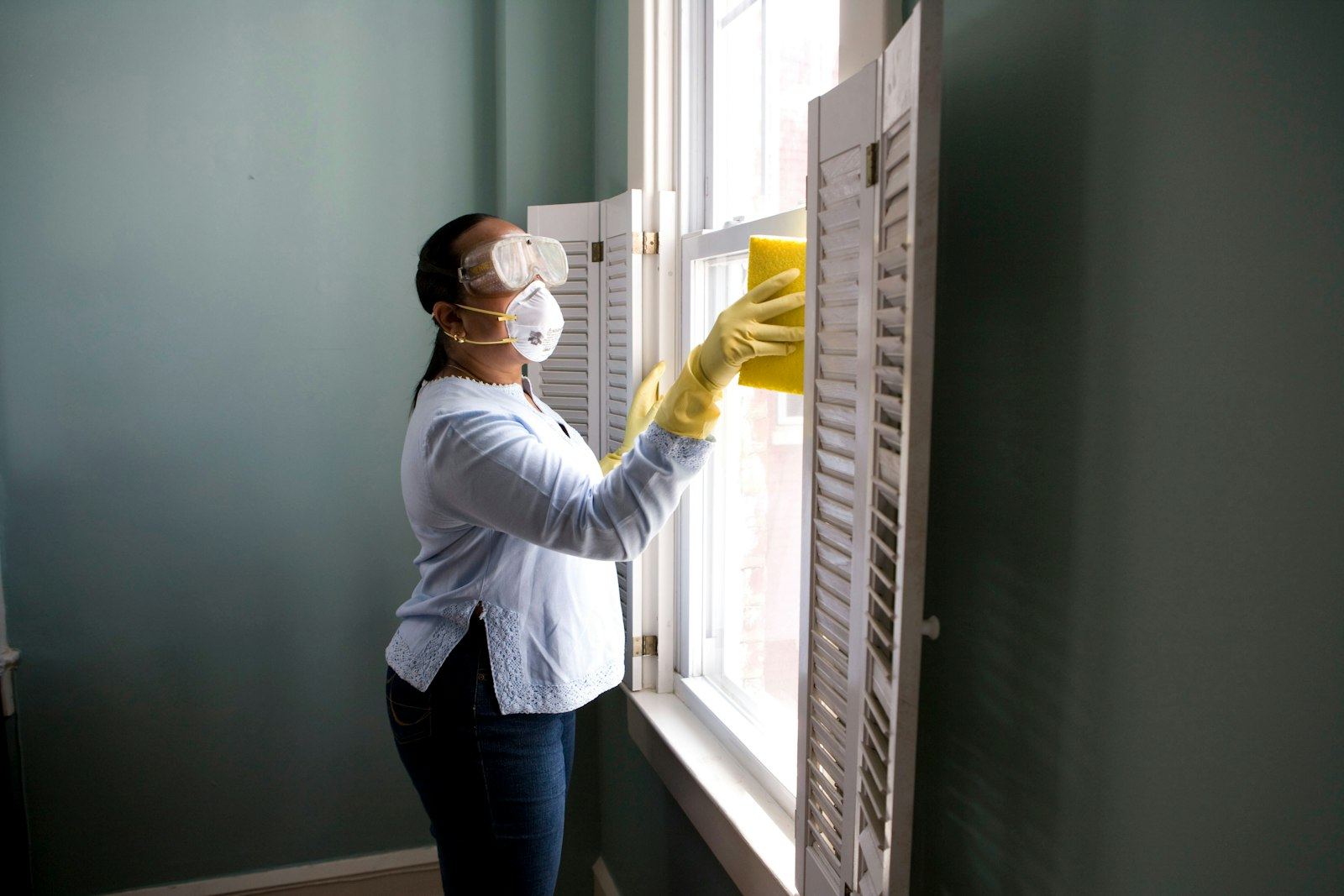 Cleaner wiping a window with a cloth and spray bottle